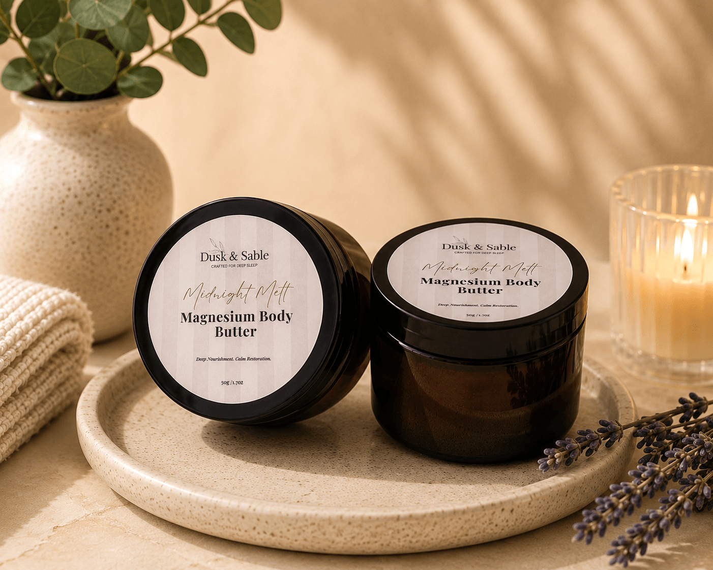 Midnight Magnesium Nourish and Restore Bundle with magnesium body butter in black jars on beige tray next to mulberry silk.